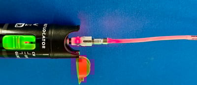 An example of red (visual) light leak at the non-locking 2.5 mm universal interface of a high-power VFL (50 mW) and through the fiber optics, causing an unknow loss. (Note: SC connector with body and boot removed for better visibility)