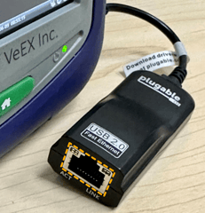 VeEX's handheld V150 test platform with external micro-B USB (OTG) to RJ54 Ethernet adapter for the Management Port